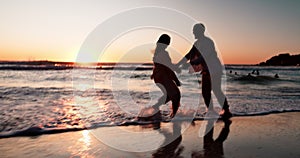 Couple, running and hug by beach in sunset, silhouette or game with love, romance or bonding on vacation. Man, woman and