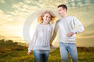 Couple running laughing and holding hands under the sky