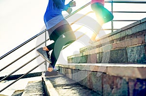 Couple running on stairs at sunset - Friends making a workout session exercising to get on staircase outdoor