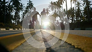 Couple running on sunny road between the palm trees. slow motion. 1920x1080