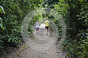 Couple running on trail at `Bosque da Freguesia` Public park in the neighborhood of Jacarepagua