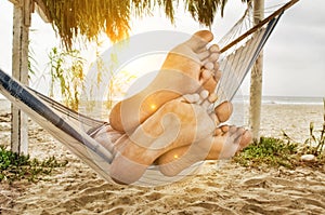 Couple`s Feet on Edge of Hammock on Beach