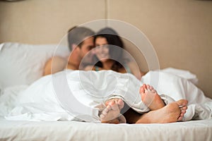 Couple`s feet under blanket.