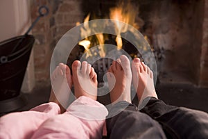 Couple's feet warming at a fireplace