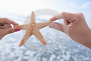 Couple`s hands holding starfish at the beach