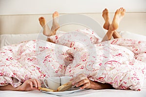 Couple's Hands Reaching From Under Duvet