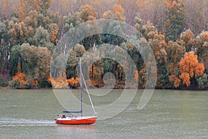 Couple sailing on small yacht in the river on beautiful autumn d