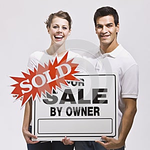 Couple with For Sale by Owner Sign