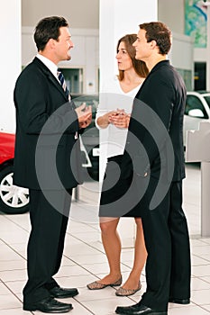 Couple with salesman at car dealer