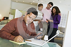 Couple And Salesperson With Man And Laptop In Foreground