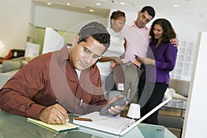 Couple And Salesperson With Man And Laptop In Foreground photo