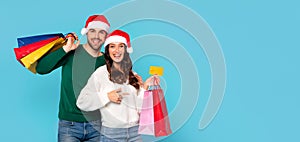 couple with Santa hats and bags holding credit card, studio