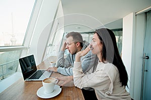 Couple saw something shoking on laptop. Man fiddles with hair and woman giggles and covers her mouth with hand. Empty photo