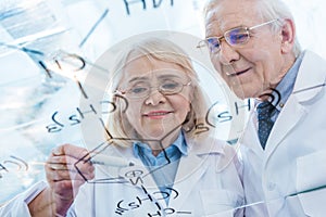 Couple of scientists in white coats working with chemical formula