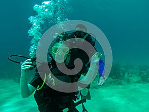 A couple scuba dive together. A female scuba diver with the regulator out. Smiling, holding the regulator. Divers. Roatan, Hondura