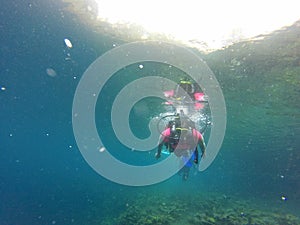 Couple scuba diving under crystal clear water with tank, fins and visor happy swim and share their love doing exercise and living