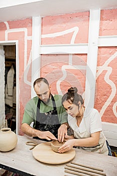 Couple of sculptors shaping clay bowl photo