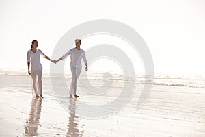 Couple, sea and holding hands while walking on beach, travel and commitment with trust and bonding outdoor. Love, care