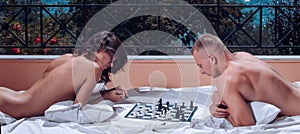 Couple at sea resort play chess. Sexy man with woman playing chess on balcony.