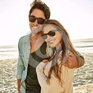 Couple, sea and sunglasses with embrace, happy or care for fashion, eye protection or vacation in summer. Man, woman and