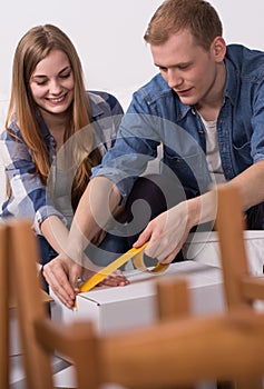 Couple sealing a moving box