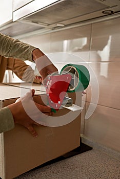 Couple sealing up cardboard box with adhesive tape