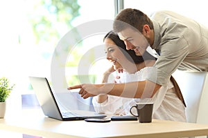 Couple searching online in a laptop at home