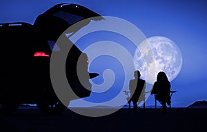 Couple Seating Next to Their Vehicle and Enjoying Full Moon Vista