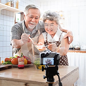 Couple senior Asian elder happy living in home kitchen. Grandfather wiping grandmother mouth after eating bread with jam vlog vdo