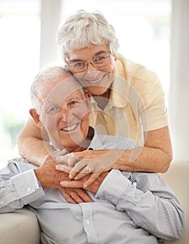 Couple, senior and hug or portrait on couch, home and relax together for bonding and smile. Elderly people, embrace and