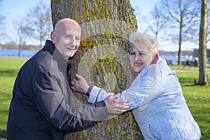 Couple senior men and women are flirting with tree in park