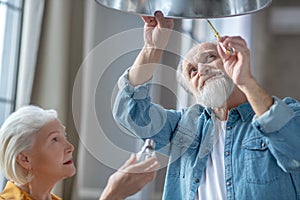 Couple of seniors changing a lightbulb together