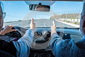 Couple of seniors driving and having fun together with a rent car in the street - two pensioners in vacations together - man and