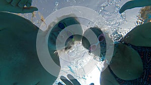 Couple of seniors enjoying summer and having fun together in the pool swimming and smiling looking at the camera - cheerful happy