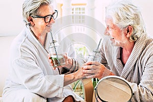 Couple of seniors having fun together in a beauty treatment drinking a cocktail and smiling - two mature people laughing and