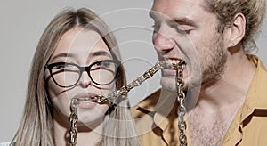 Couple of sexy man and sensual woman. Portrait of sexy coupl. Trendy look. Chains in mouth.