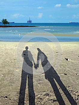 couple shadows holding hands at sandy beach