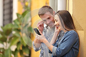 Couple sharing earphones to watch media on phone