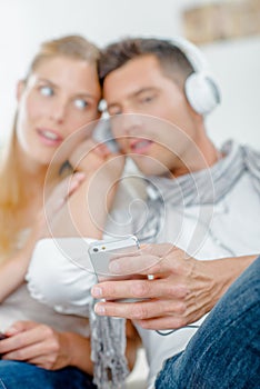 Couple sharing headphones listening to cellphone