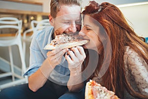 Couple sharing pizza and eating