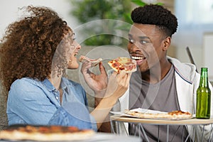 couple sharing pizza and eating together happily in kitchen