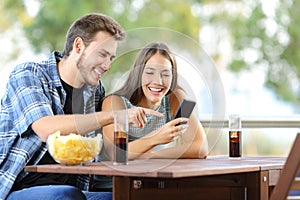 Couple sharing a smart phone outdoors