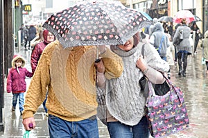 Couple shelter under umbrella In Heavy Rain in the ,UK.