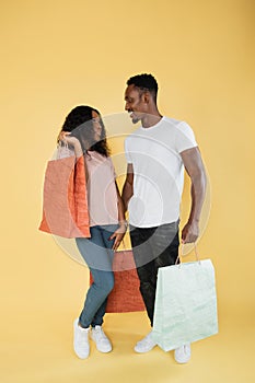 Couple of shopaholics. African american man and woman holding shopping bags.