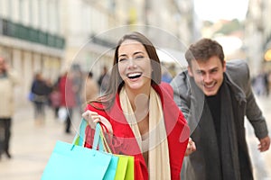 Couple of shoppers running with shopping bags photo