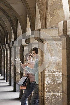 Couple With Shopping Bags Looking At Map