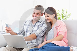 Couple shopping online through laptop using credit card