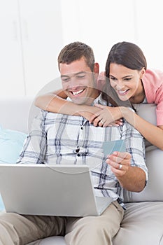 Couple shopping online through laptop using debit card