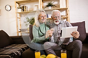 Couple shopping online with tablet and credit card at home