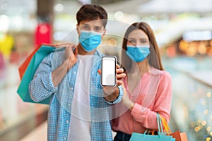 Couple Shopping Showing Smartphone Screen Wearing Face Mask In Mall